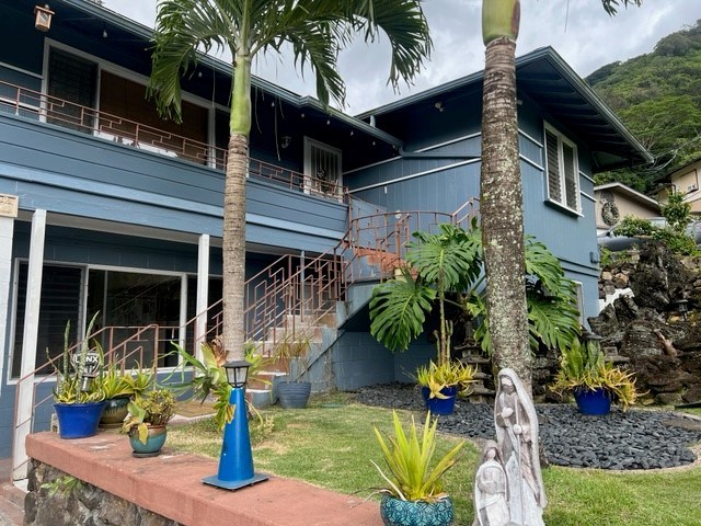 A blue house with a balcony and a tree in front.